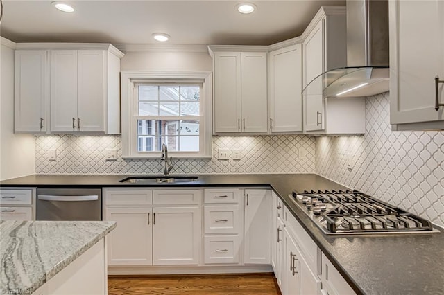 kitchen featuring white cabinetry, stainless steel appliances, sink, and wall chimney range hood