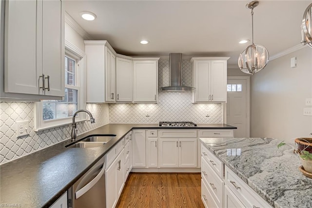 kitchen featuring sink, appliances with stainless steel finishes, wall chimney range hood, light hardwood / wood-style floors, and white cabinets