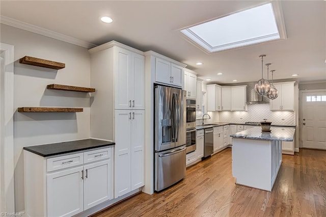 kitchen featuring appliances with stainless steel finishes, sink, hanging light fixtures, and white cabinets