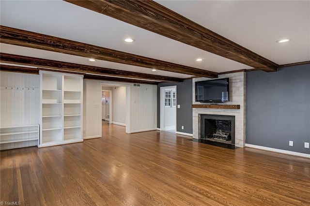 unfurnished living room with hardwood / wood-style flooring, a fireplace, built in features, and beamed ceiling