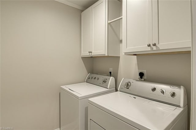 clothes washing area featuring washer and clothes dryer and cabinets