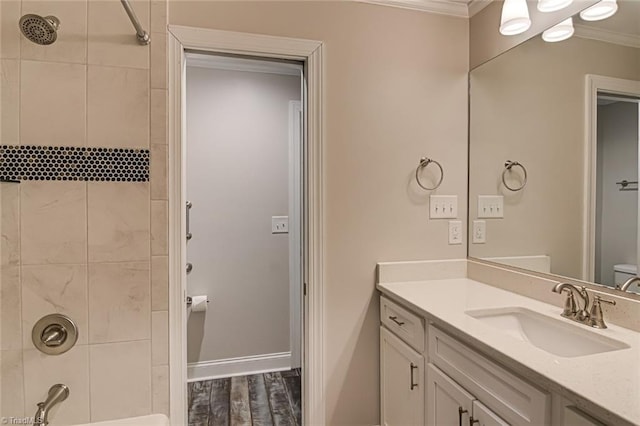 full bathroom featuring crown molding, hardwood / wood-style flooring, tiled shower / bath combo, vanity, and toilet