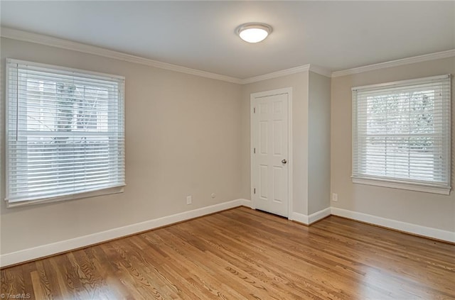 spare room featuring crown molding and light hardwood / wood-style floors