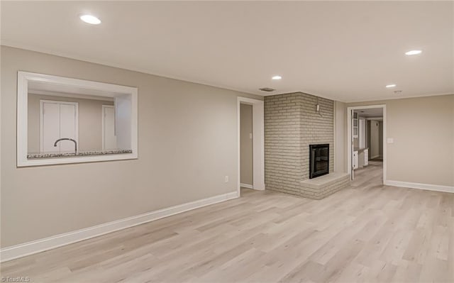 unfurnished living room featuring a brick fireplace and light wood-type flooring