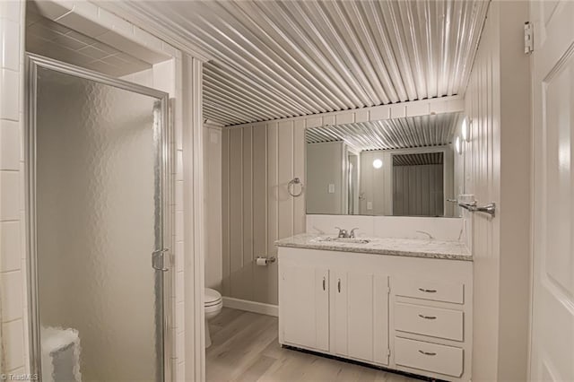 bathroom with a shower with door, vanity, hardwood / wood-style flooring, and toilet