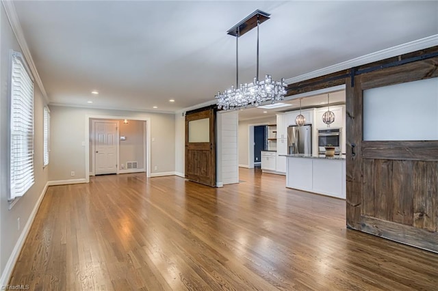 unfurnished dining area featuring crown molding, wood-type flooring, and a barn door