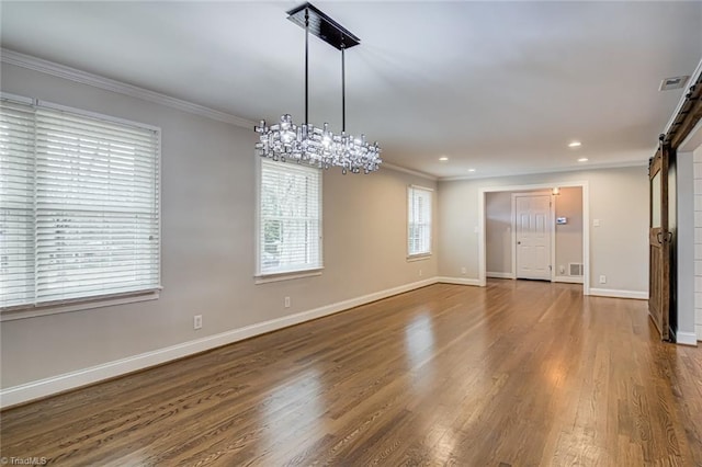 spare room with ornamental molding, a barn door, and dark hardwood / wood-style flooring