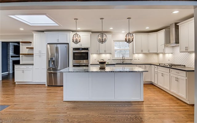 kitchen with dark stone countertops, hanging light fixtures, wall chimney exhaust hood, and appliances with stainless steel finishes