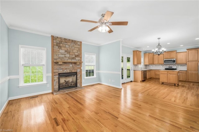 unfurnished living room featuring ceiling fan with notable chandelier, ornamental molding, light hardwood / wood-style floors, and a fireplace