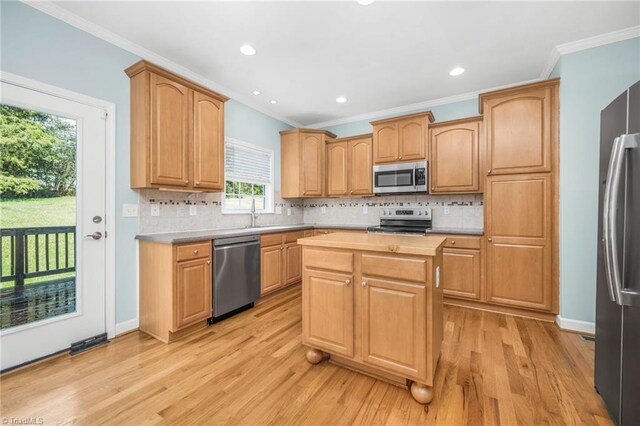 kitchen featuring ornamental molding, stainless steel appliances, light hardwood / wood-style floors, and tasteful backsplash