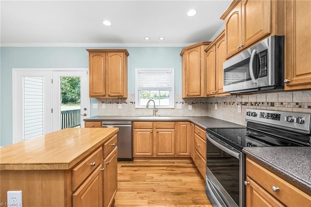 kitchen with light hardwood / wood-style floors, sink, decorative backsplash, appliances with stainless steel finishes, and crown molding