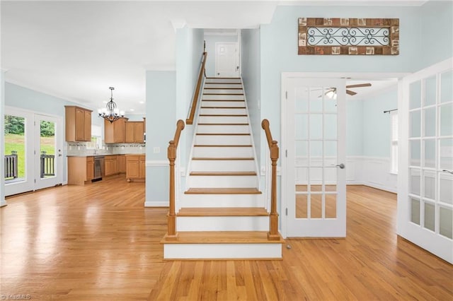 stairway featuring hardwood / wood-style flooring, ceiling fan with notable chandelier, crown molding, and beverage cooler