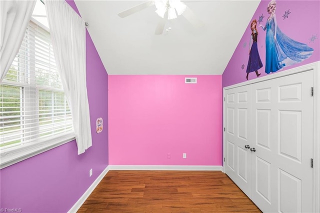 unfurnished bedroom featuring ceiling fan, vaulted ceiling, a closet, and hardwood / wood-style floors