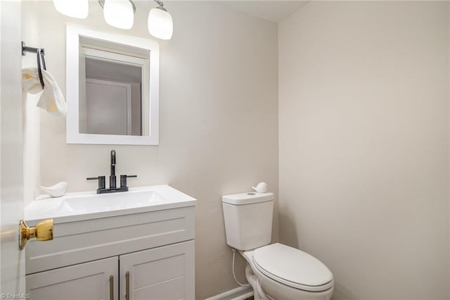 bathroom featuring toilet, baseboards, and vanity