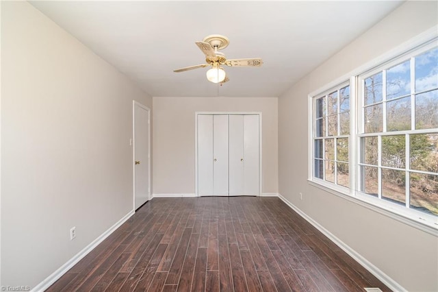 unfurnished bedroom featuring dark wood-style flooring, a closet, a ceiling fan, and baseboards