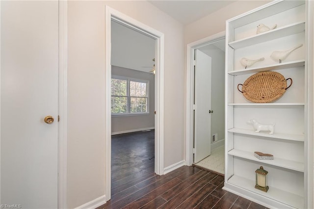 hallway featuring baseboards and dark wood-style flooring