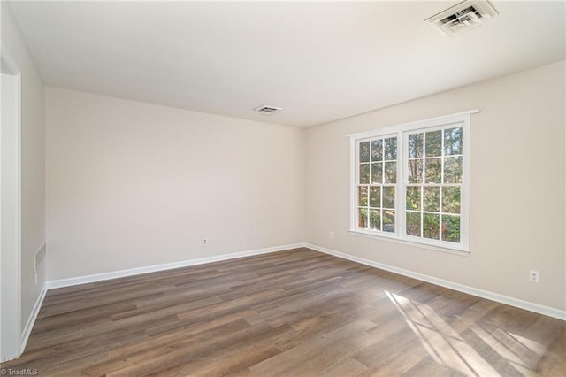 spare room with baseboards, visible vents, and dark wood finished floors