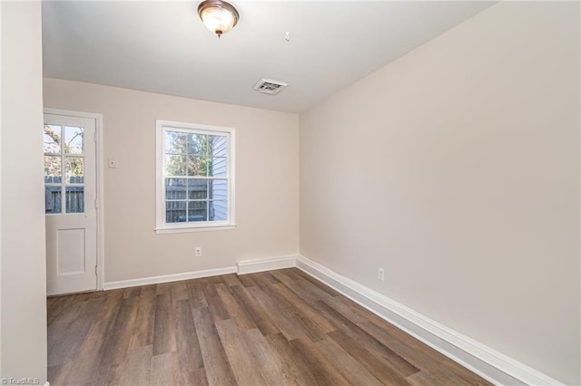 unfurnished room with dark wood-type flooring, visible vents, and baseboards