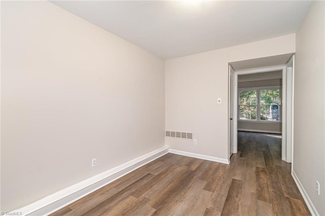 empty room with visible vents, baseboards, and dark wood-type flooring