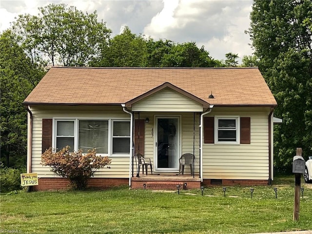 bungalow-style home with a front lawn, roof with shingles, and crawl space
