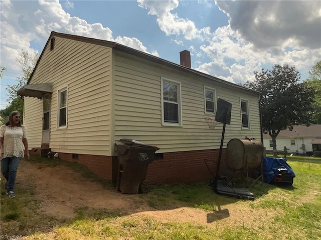 view of side of home with a chimney, heating fuel, and crawl space