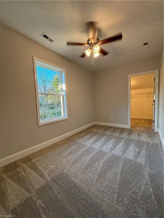 unfurnished bedroom featuring carpet flooring, a walk in closet, ceiling fan, and a closet