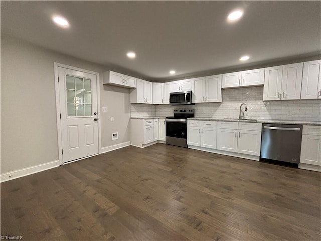 kitchen with appliances with stainless steel finishes, backsplash, sink, dark hardwood / wood-style floors, and white cabinetry