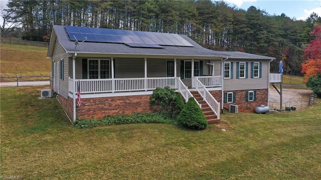 view of front of property with central air condition unit, a front yard, a porch, and solar panels