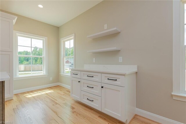 interior space with open shelves, light wood-style floors, baseboards, recessed lighting, and white cabinetry