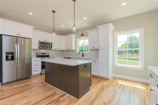 kitchen with light countertops, stainless steel appliances, white cabinetry, and a sink