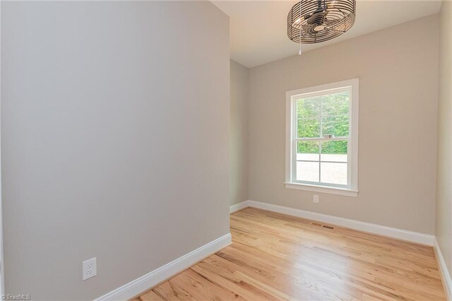 spare room with baseboards, light wood-type flooring, and visible vents