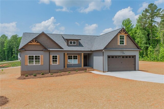 craftsman-style house with a shingled roof, covered porch, and concrete driveway