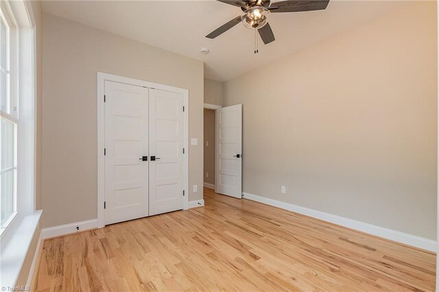 unfurnished bedroom featuring baseboards, a ceiling fan, a closet, and light wood finished floors
