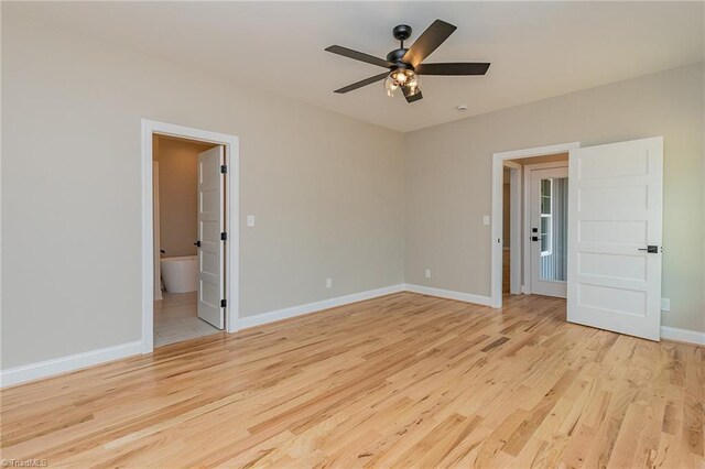 unfurnished bedroom featuring baseboards, ceiling fan, wood finished floors, and ensuite bath