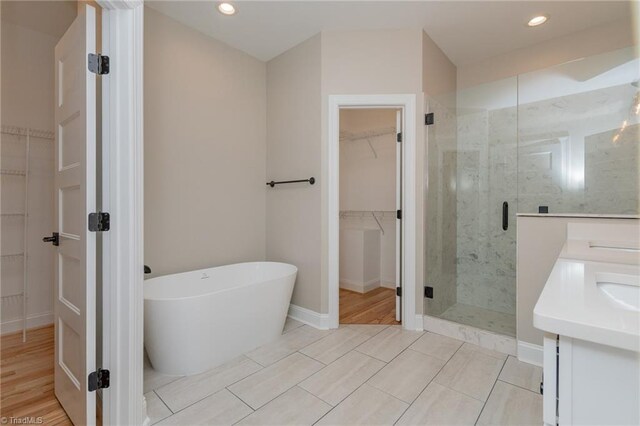 full bath featuring double vanity, a freestanding tub, recessed lighting, and a stall shower