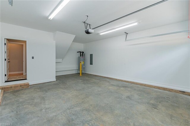 garage featuring baseboards, a garage door opener, and water heater