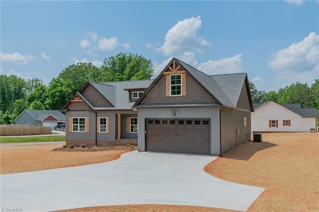 craftsman-style house featuring a garage, board and batten siding, central air condition unit, and driveway