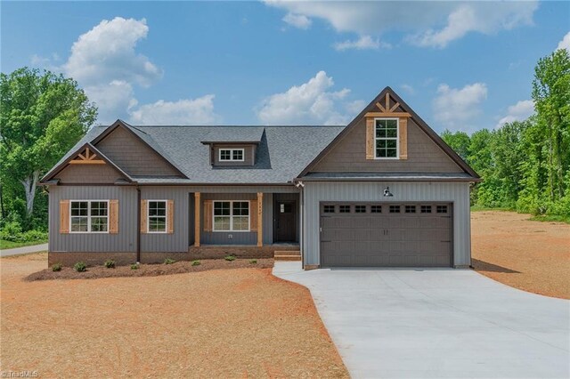 craftsman inspired home featuring roof with shingles, an attached garage, board and batten siding, concrete driveway, and covered porch