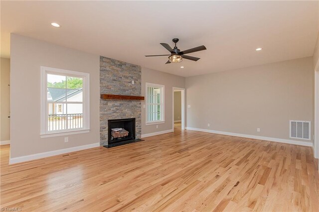 unfurnished living room featuring visible vents, a fireplace, baseboards, light wood-type flooring, and a ceiling fan