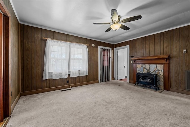 unfurnished living room with ornamental molding, ceiling fan, light colored carpet, and wooden walls