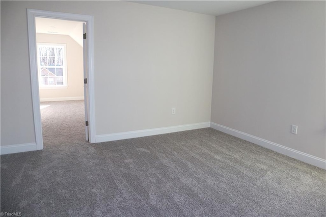 empty room with vaulted ceiling and dark colored carpet