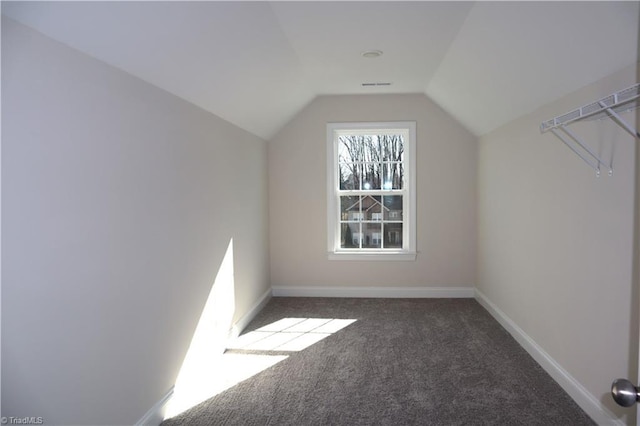 bonus room with dark colored carpet and lofted ceiling