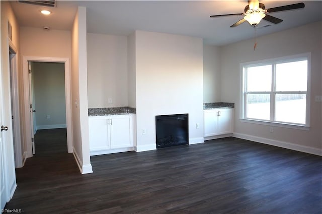 unfurnished living room featuring ceiling fan and dark wood-type flooring