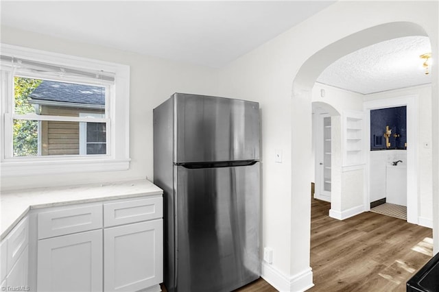 608 Spruce St, High Point, NC 27262 - kitchen with freestanding refrigerator, arched walkways, wood finished floors, white cabinets, and a textured ceiling