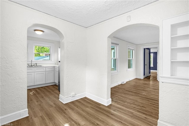 608 Spruce St, High Point, NC 27262 - corridor featuring a textured wall, wood finished floors, a textured ceiling, built in features, and arched walkways