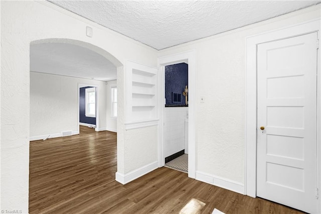 608 Spruce St, High Point, NC 27262 - empty room featuring a textured ceiling, arched walkways, built in features, dark wood finished floors, and a textured wall