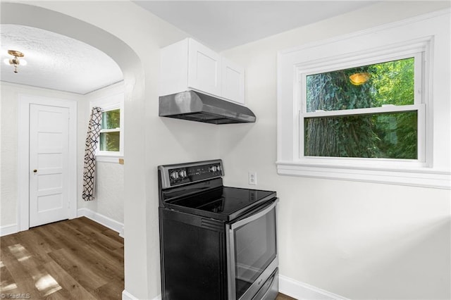 608 Spruce St, High Point, NC 27262 - kitchen featuring stainless steel electric stove, range hood, dark wood-style floors, white cabinets, and arched walkways