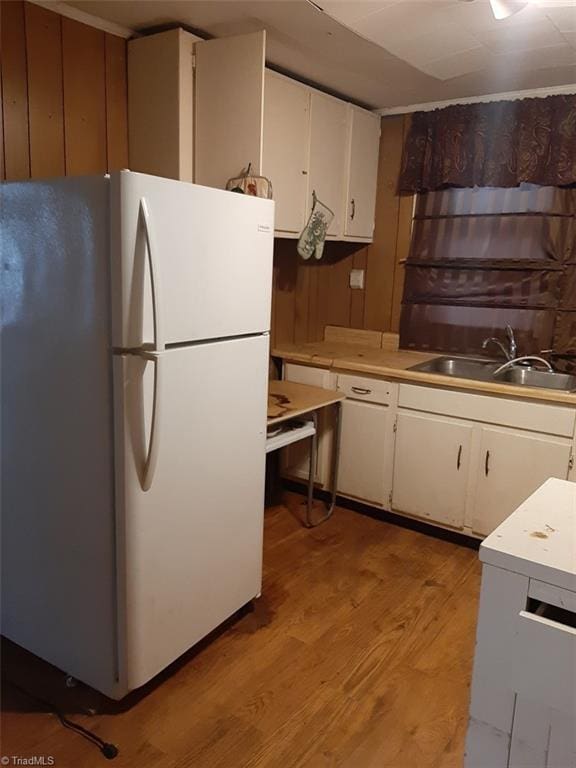 kitchen with white cabinets, white fridge, light hardwood / wood-style floors, and sink