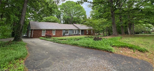 single story home with a front yard, driveway, and brick siding