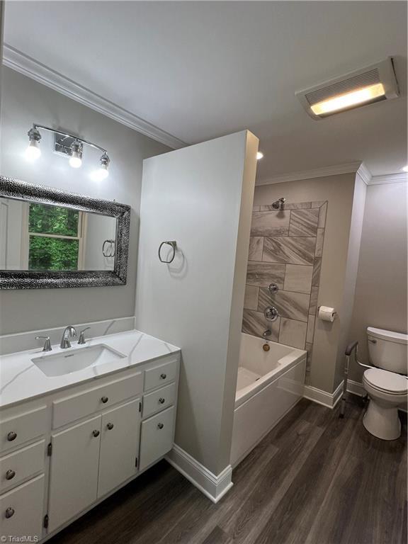 full bath with toilet, baseboards, ornamental molding, and wood finished floors